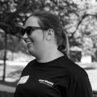 Black and white picture of GVSU Alumna smiling as she carries a box